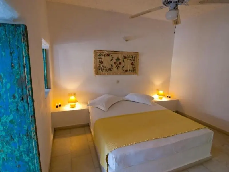 Une chambre lumineuse avec un lit recouvert d'un couvre-lit jaune.