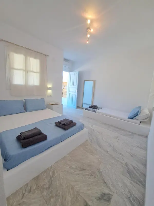 Une chambre lumineuse avec deux lits et un décor blanc.