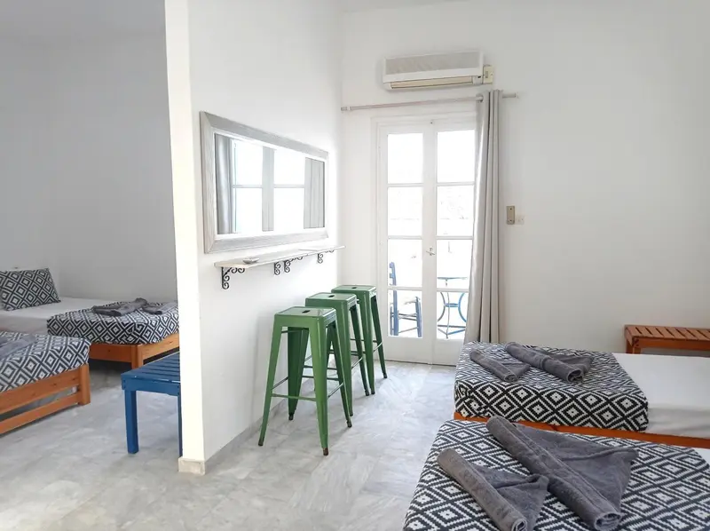 Une chambre lumineuse avec des lits simples et une porte-fenêtre donnant sur une terrasse.