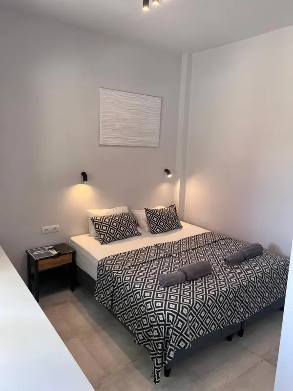 Une chambre lumineuse avec un grand lit recouvert d'une couette à motifs géométriques.