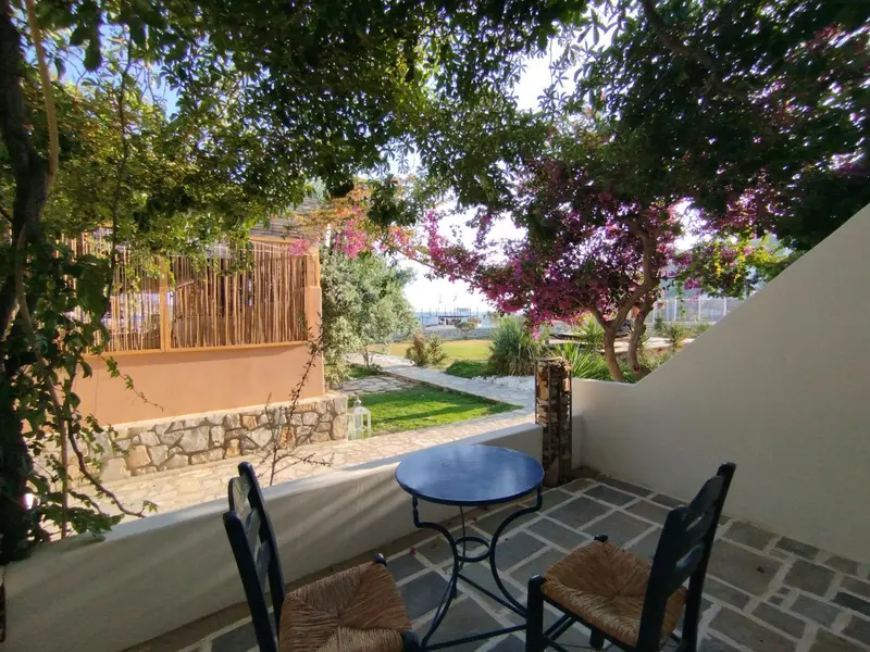 Terrasse ombragée avec mobilier en fer forgé donnant sur un jardin verdoyant.
