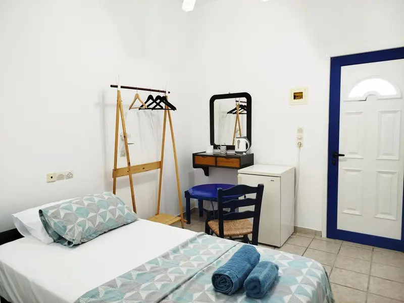 Une chambre lumineuse avec un lit simple et un espace rangement.