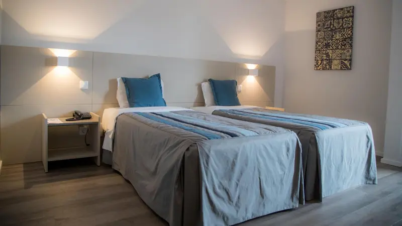 Une chambre lumineuse avec deux lits simples et une décoration sobre.