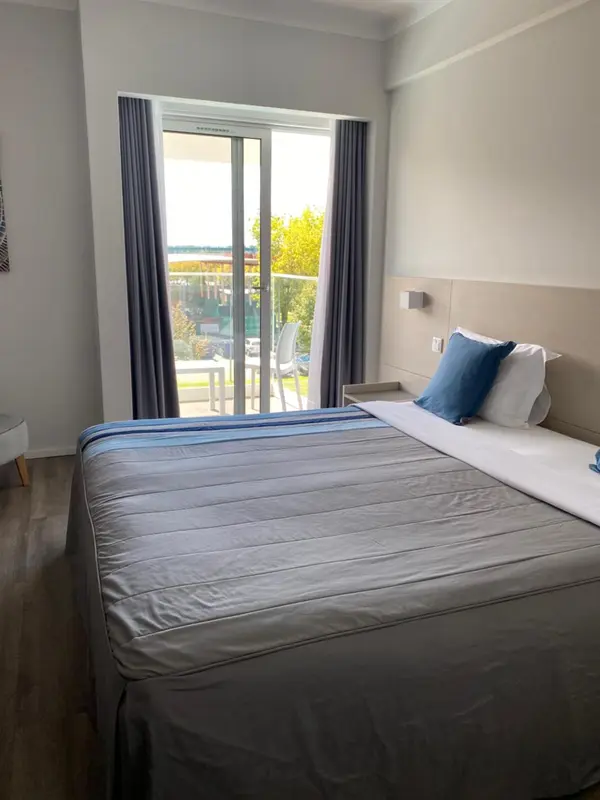 Une chambre lumineuse avec un lit et un accès à une terrasse.