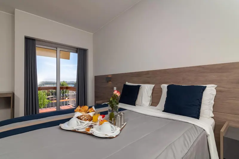 Un petit-déjeuner est servi sur un plateau posé sur un lit dans une chambre.