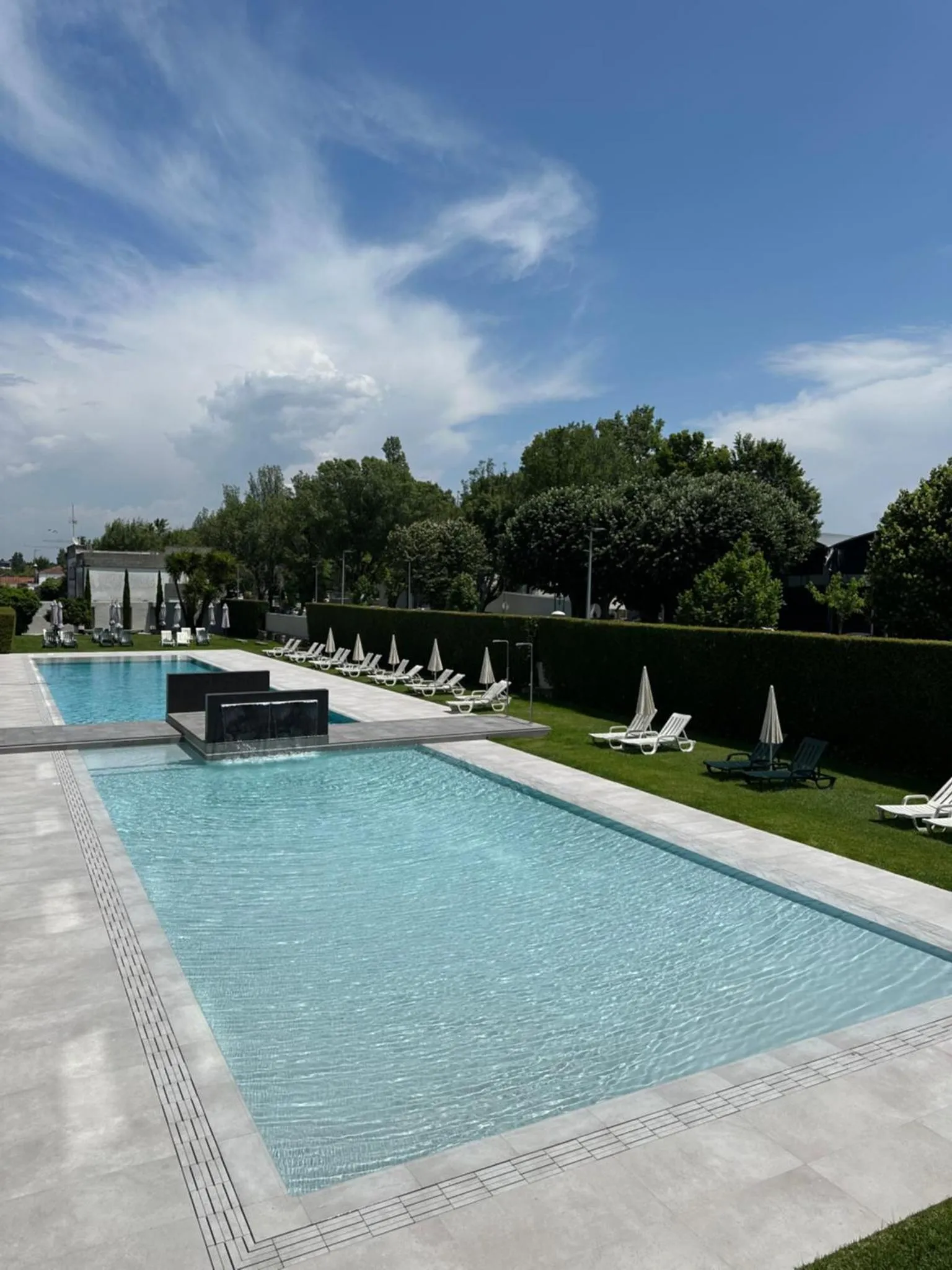 Une piscine rectangulaire bordée d'une terrasse ensoleillée avec des transats.