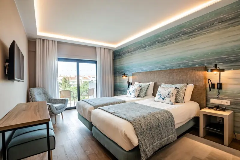 Chambre lumineuse avec deux lits simples et un décor mural évoquant la mer.