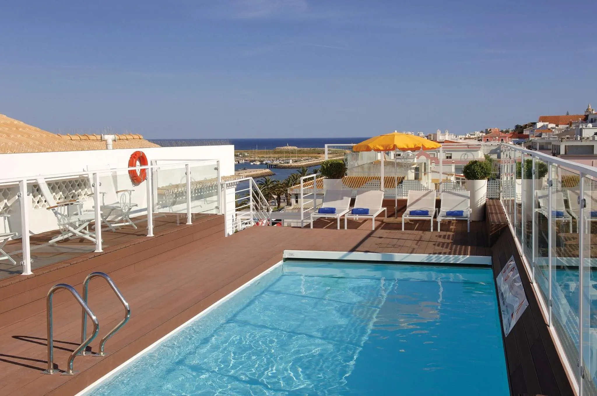 Terrasse avec piscine et vue sur la mer et un port.