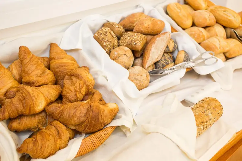 Assortiment de viennoiseries et de pains frais présentés sur un buffet.