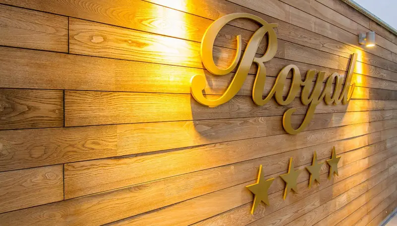 Lettres dorées formant un nom sur un mur en bois clair.