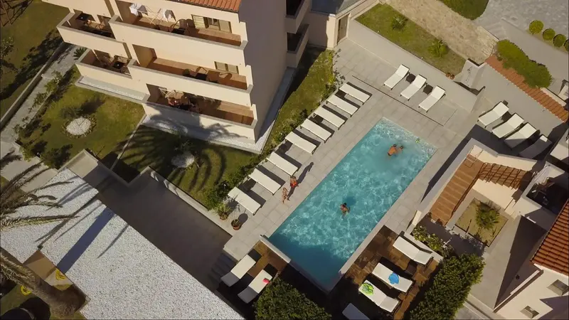 Vue aérienne d'une piscine rectangulaire entourée de transats et d'une végétation soignée.