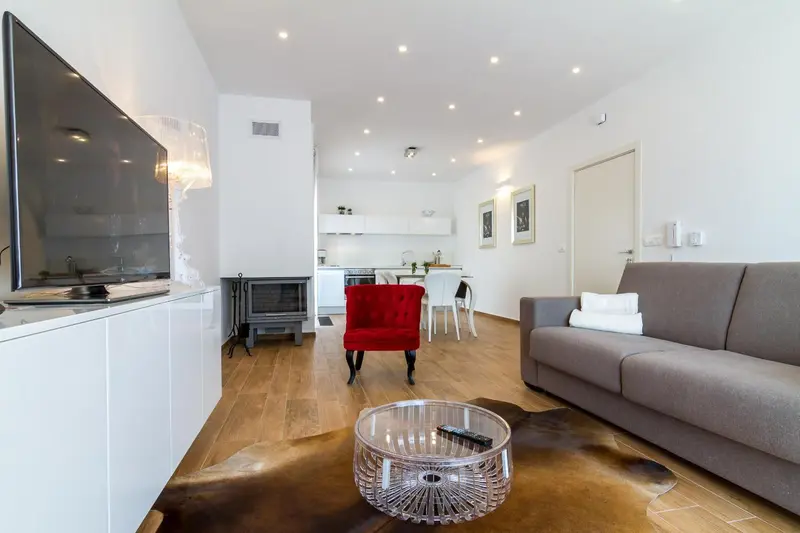 Espace de vie lumineux avec canapé, télévision et coin repas.