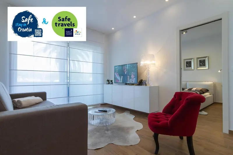 Espace de séjour lumineux avec canapé, fauteuil et télévision.