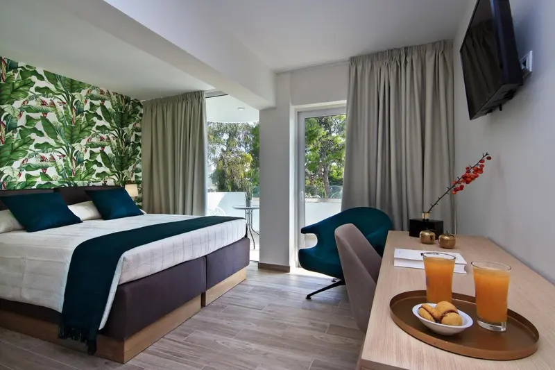 Une chambre lumineuse avec un lit double et un coin salon donnant sur une terrasse.