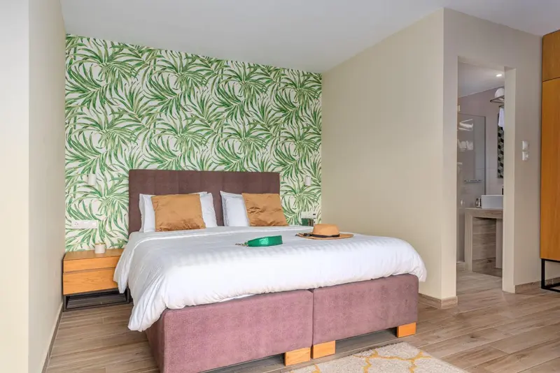 Une chambre lumineuse avec un grand lit et un mur végétal.
