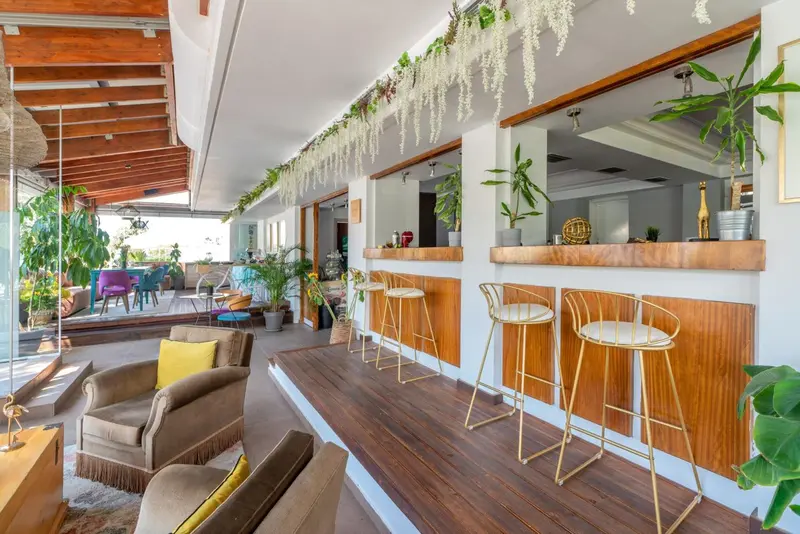 Un espace bar lumineux avec des tabourets et des fauteuils confortables.