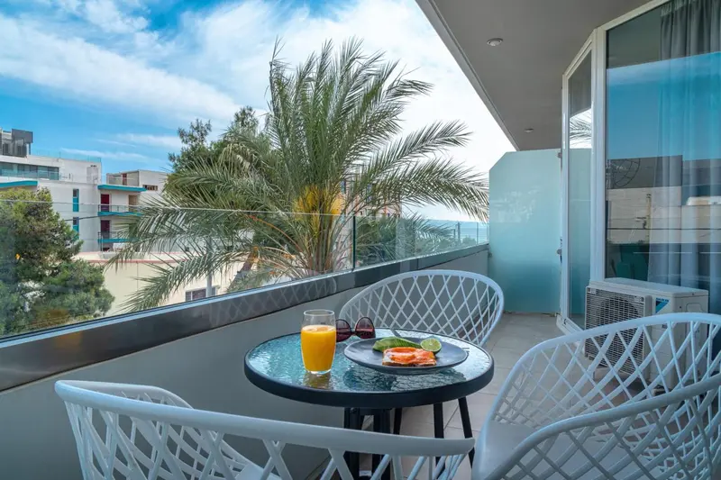 Une table avec des boissons et des fruits est mise en scène sur une terrasse ensoleillée.