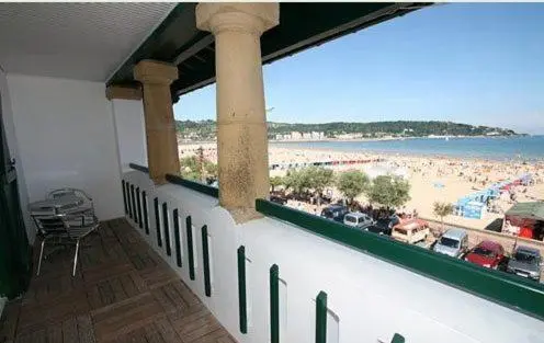 Terrasse carrelée avec mobilier donnant sur une plage animée et la mer.