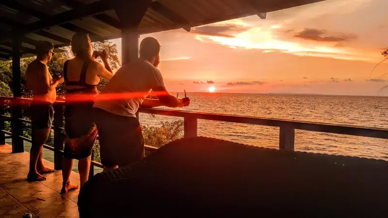 Des personnes observent le coucher de soleil depuis une terrasse.
