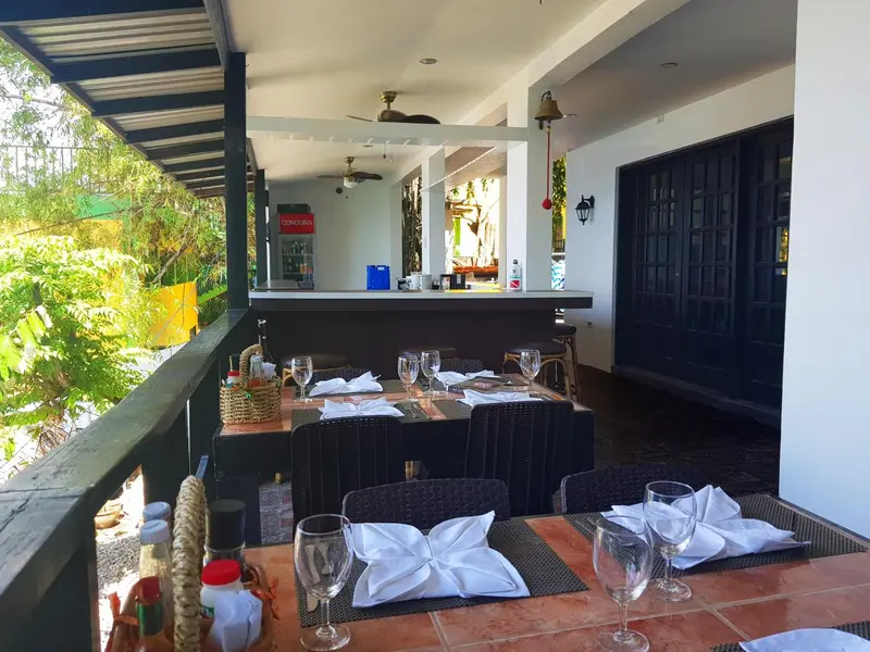 Une terrasse ombragée abrite des tables préparées pour un repas.