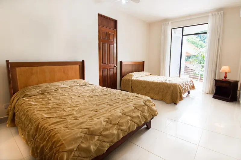 Une chambre lumineuse avec deux lits simples et une vue sur l'extérieur.