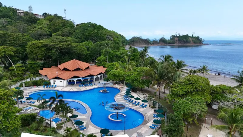 Vue aérienne d'un complexe hôtelier avec piscine et accès à la plage.