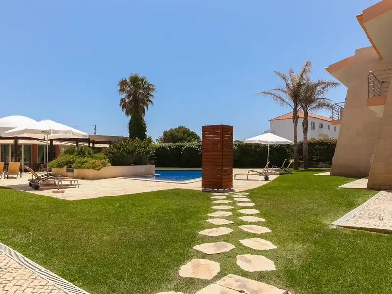 Une piscine bordée de chaises longues et d'une pelouse verdoyante dans un complexe hôtelier.