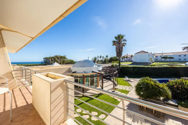 Terrasse carrelée avec vue sur un jardin verdoyant et la mer.