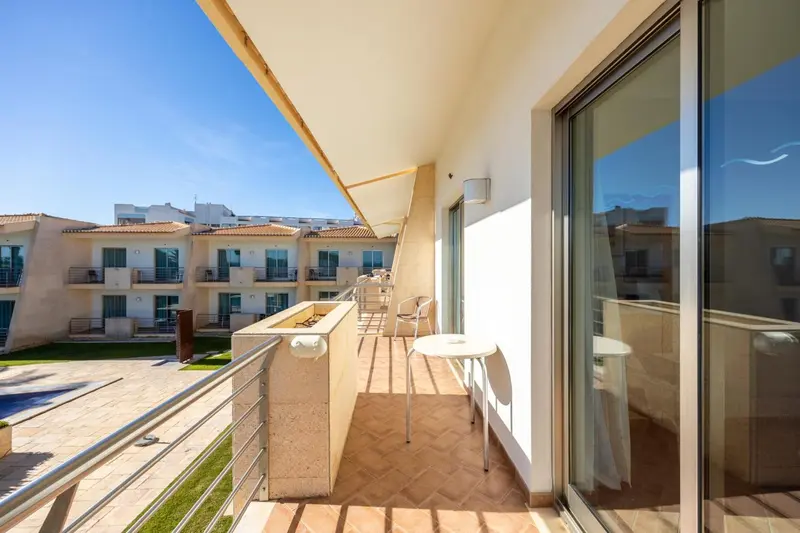 Balcon avec mobilier d'extérieur donnant sur un paysage urbain et une piscine.