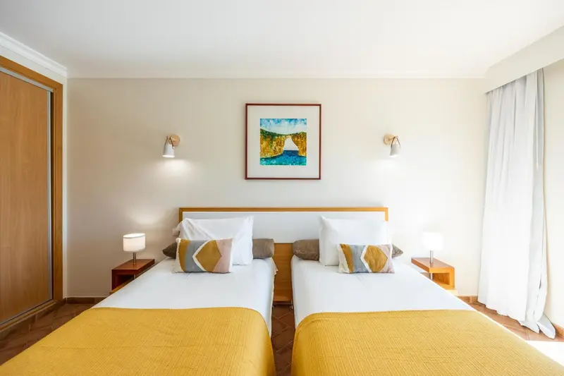 Une chambre lumineuse avec deux lits simples et une décoration sobre.
