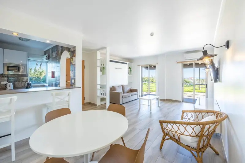 Espace de vie lumineux avec coin repas et canapé près d'une baie vitrée.