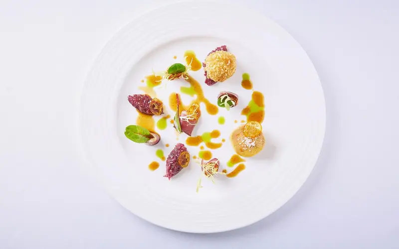 Assiette raffinée avec une présentation artistique de plusieurs éléments culinaires.