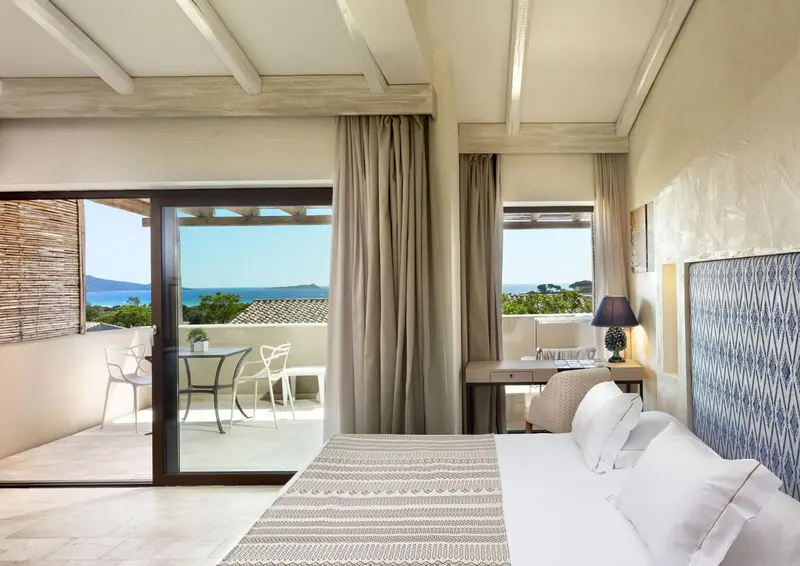 Chambre lumineuse avec un lit et un accès à une terrasse offrant une vue sur la mer.