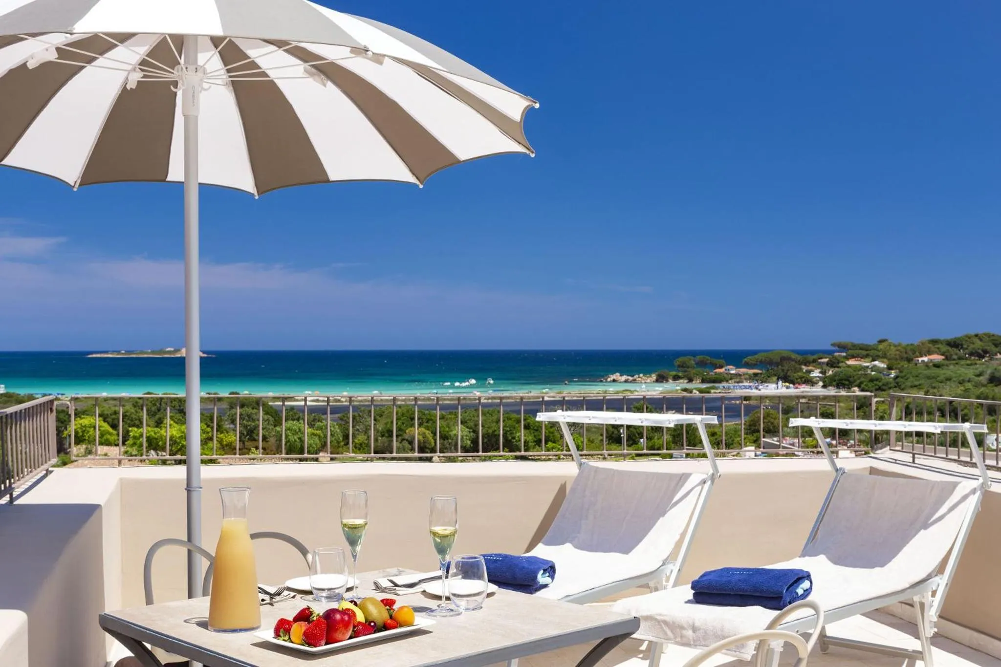 Terrasse avec transats, table et vue sur la mer.