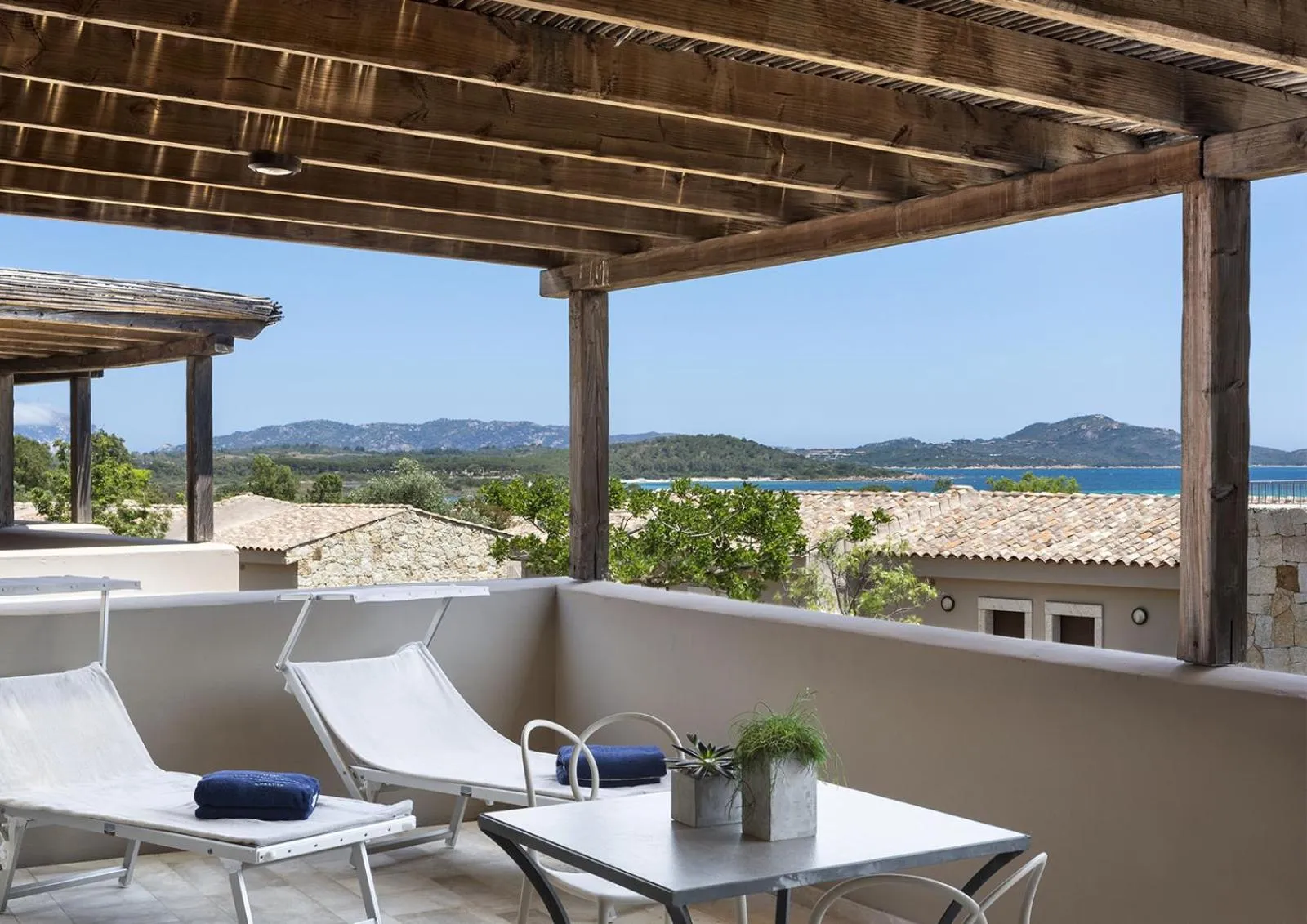 Terrasse ombragée avec mobilier de détente et vue sur la mer.