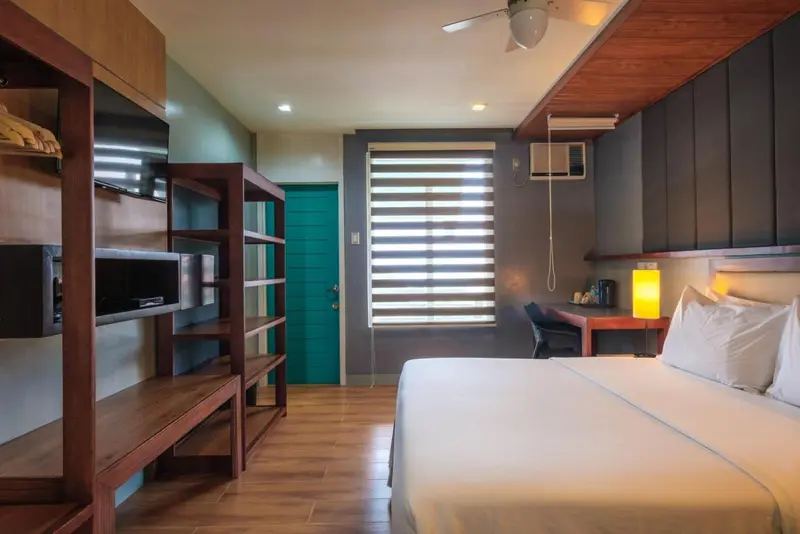 Une chambre lumineuse avec un lit double et un meuble télévision.
