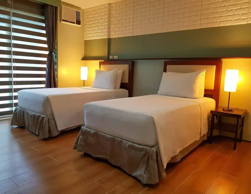Une chambre lumineuse avec deux lits simples et des lampes de chevet.