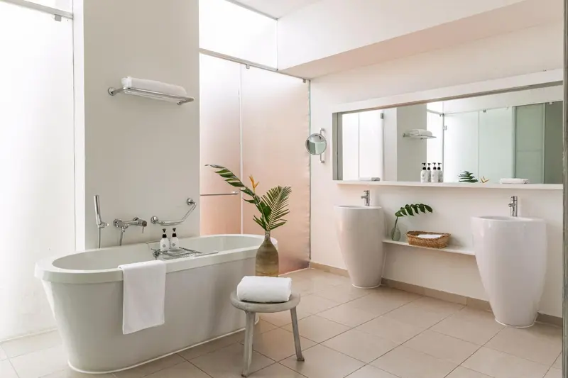 Une salle de bain lumineuse avec baignoire et deux vasques.