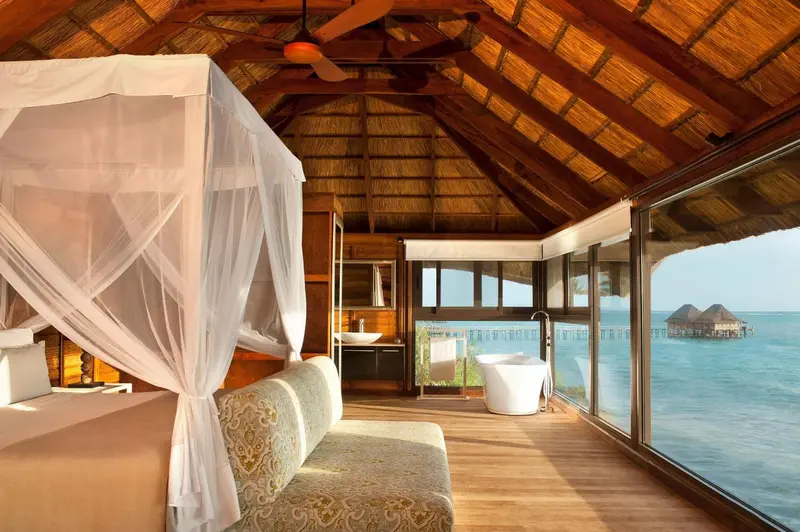Une chambre avec un lit à baldaquin et une salle de bain donnant sur l'océan.