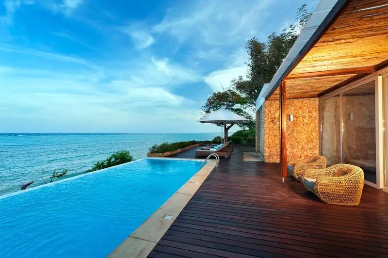 Terrasse en bois avec piscine à débordement donnant sur la mer.