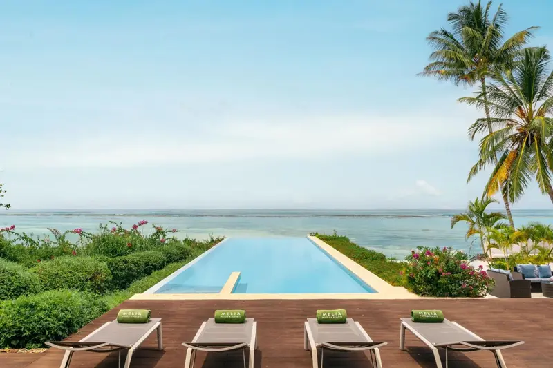 Transats alignés au bord d'une piscine à débordement avec vue sur la mer.