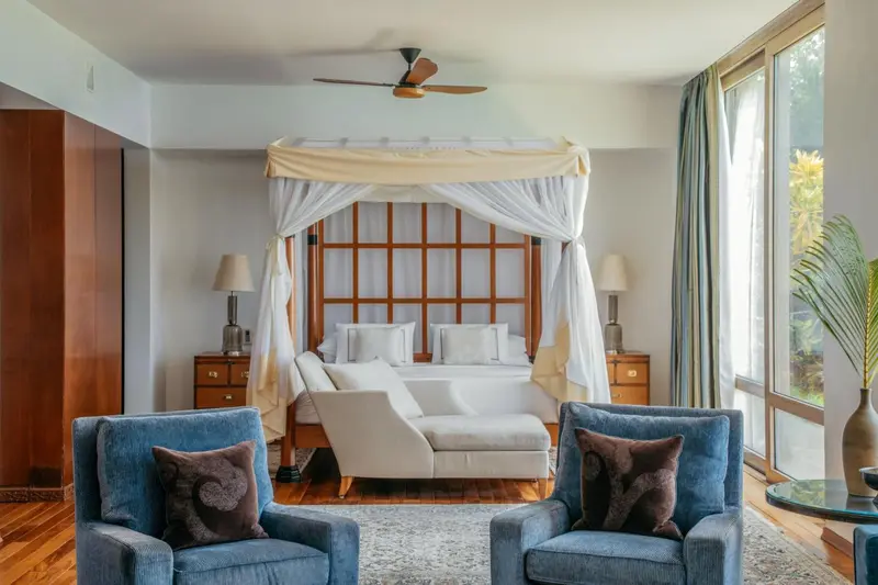 Une chambre lumineuse avec un grand lit à baldaquin et un coin salon.