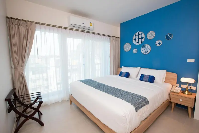Une chambre lumineuse avec un lit double et un mur bleu décoré.