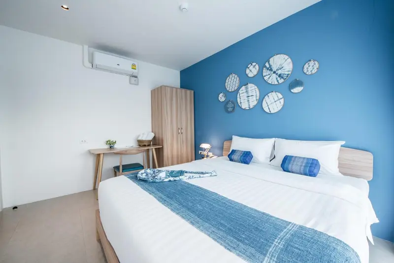 Une chambre lumineuse avec un grand lit recouvert d'une courtepointe blanche et bleue.
