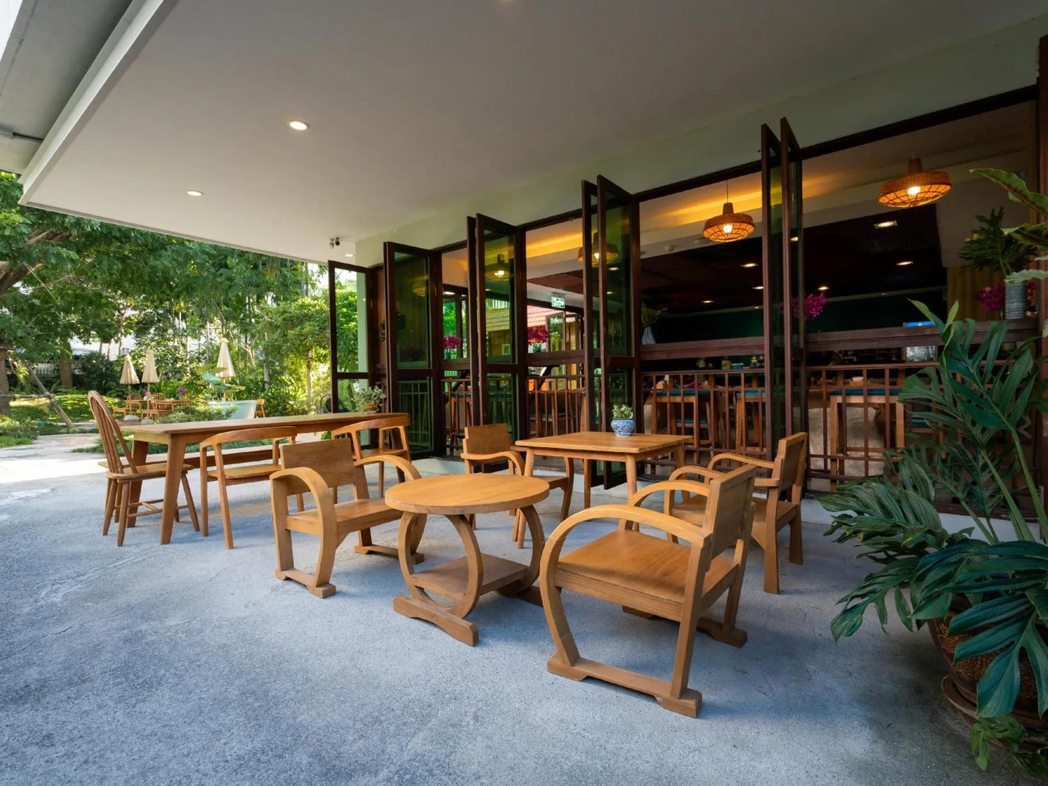 Terrasse ombragée avec tables et chaises en bois.