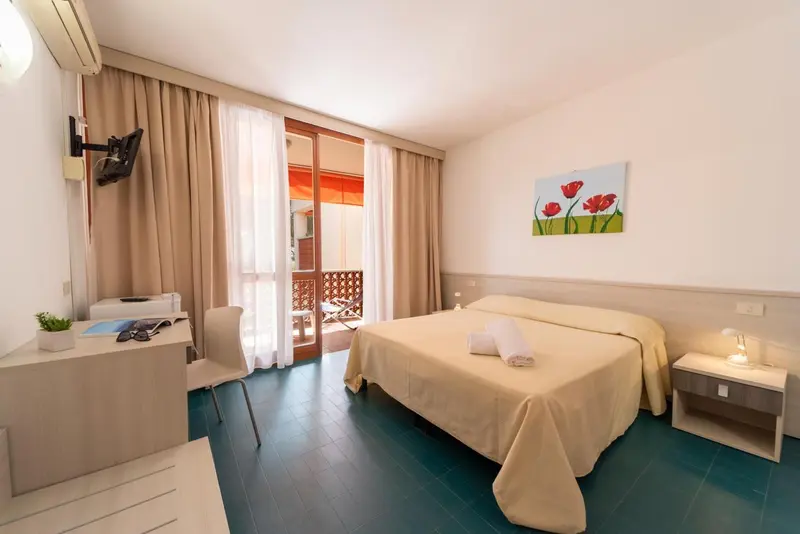 Une chambre lumineuse avec un lit double et un accès à une terrasse.