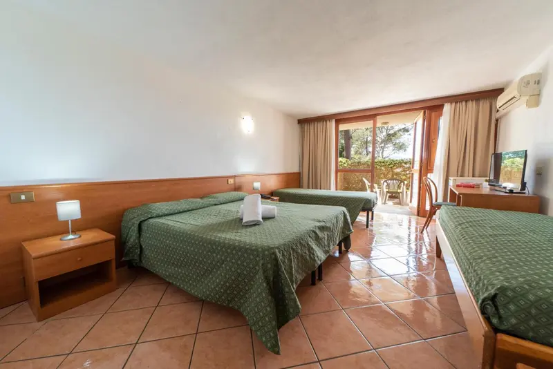 Chambre avec deux lits jumeaux et vue sur un jardin.