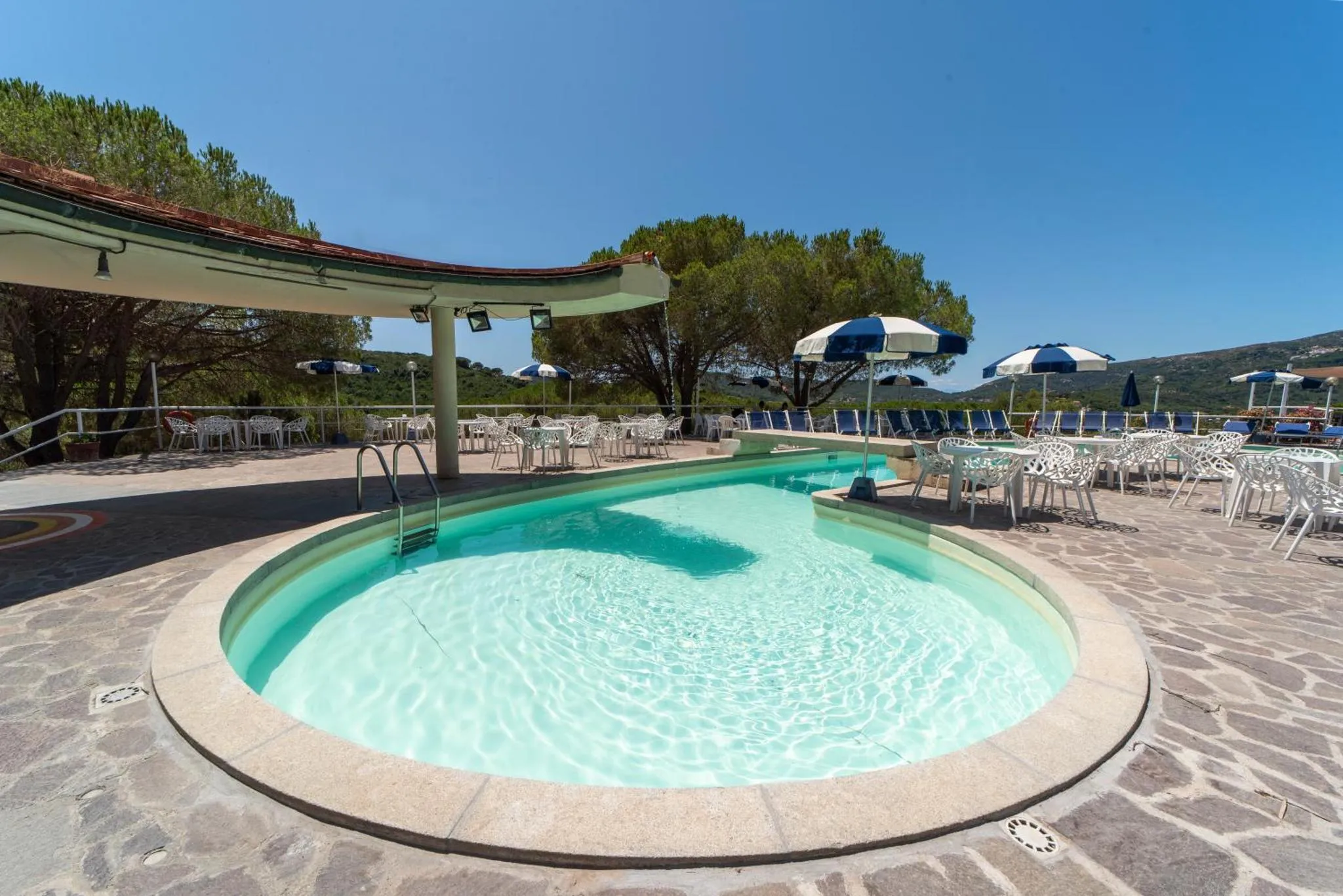 Une piscine rectangulaire entourée d'une terrasse avec des transats et des parasols.