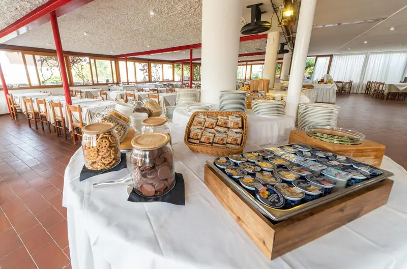 Un buffet propose des viennoiseries, des céréales et des yaourts dans une salle lumineuse.