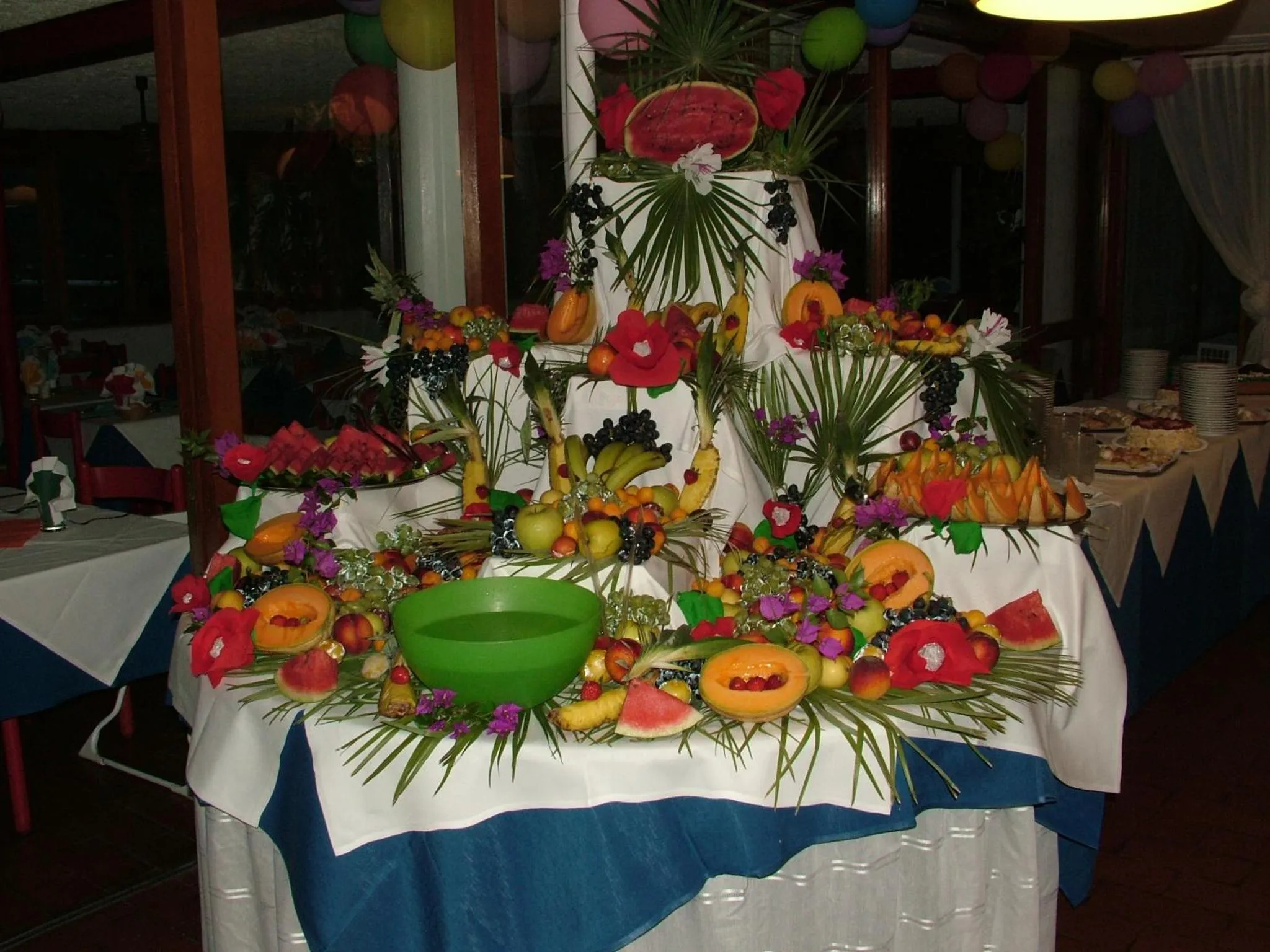Une table richement décorée de fruits frais et sculptés est présentée dans une salle.